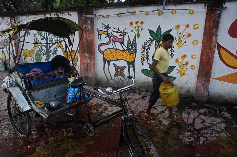 Cycle rickshaw rider washing his engine in the street, mural paintings, Hazaribagh, Jharkhand, India, Asia