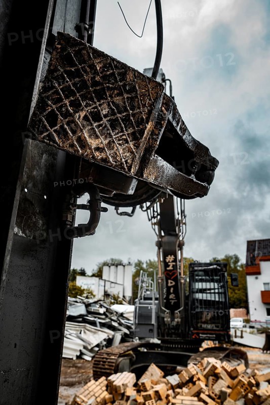 Close-up of the grab of an excavator, in the background a construction site with rubble and clouds, demolition, Saarbruecken, Germany, Europe
