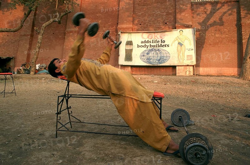 Young man lifting weights in a bodybuilding training place, Coca cola advertisement, Multan, Pakistan, Asia