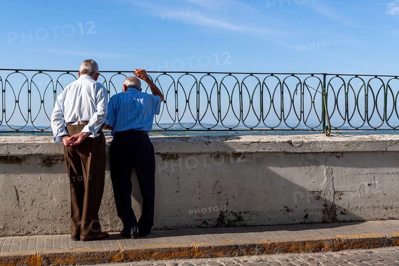 Senior citizen looking over a parapet on the street, Vejer, Andalusia, Spain, Europe