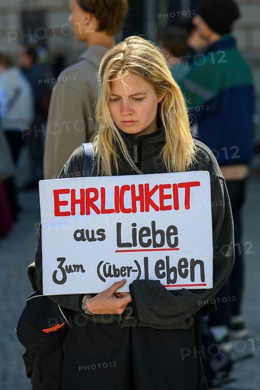 Participant in a silent demonstration for the hunger strikers. Her poster reads Honesty for the love of (survival) life . Paul Loebe House, Berlin, 12 May 2024