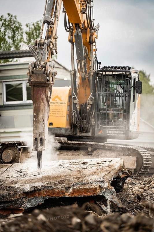 An excavator breaks up concrete on a construction site, steam rises, rubble and grey sky can be seen in the background, demolition, Saarbruecken, Germany, Europe