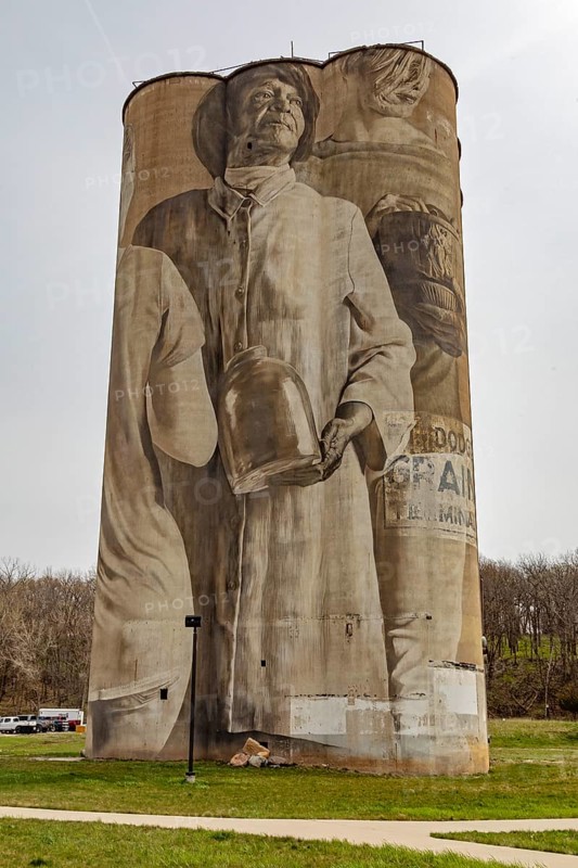 Fort Dodge, Iowa, A mural on the disused Fort Dodge Grain Terminal shows seven figures representing the people of the community. It was painted by Australian muralist Guido van Helten in 2018. Each figure carries a different stoneware object, typical of those made from the clay found in the area