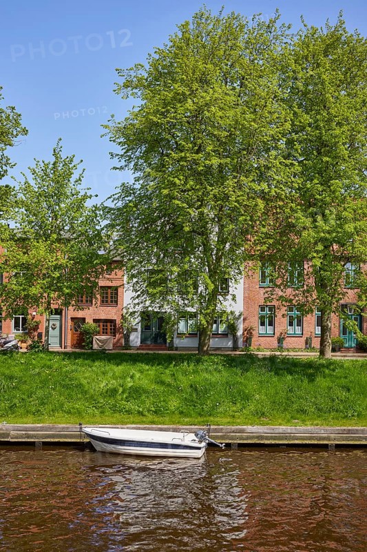 Motorboat on the Mittelburggraben with trees and houses in Friedrichstadt, district of Nordfriesland, Schleswig-Holstein, Germany, Europe