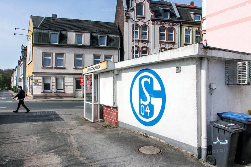 A pedestrian walks past a kiosk in Gelsenkirchen with a large S04 logo of FC Schalke 04 on it, Gelsenkirchen