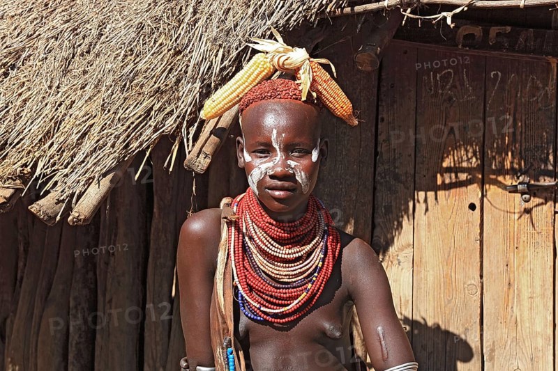 South Ethiopia, Omo region, among the Karo people, young woman, girl with jewellery and face painting sitting in front of a hut, Ethiopia, Africa