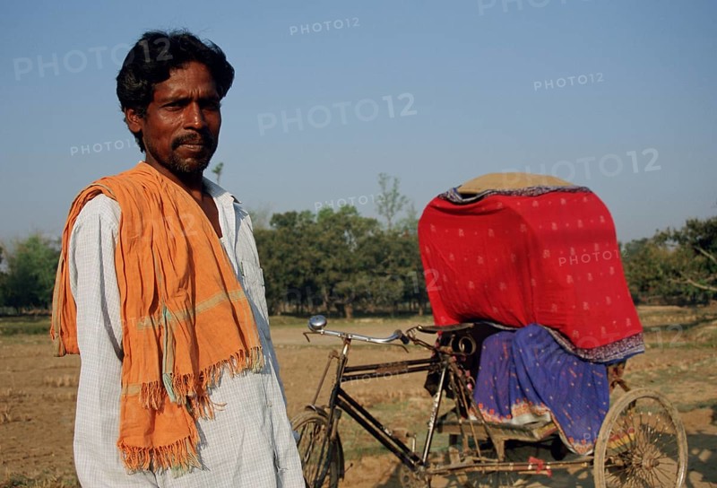 Cycle rickshaw rider, transporting a newlywed muslim couple, following the purdah tradition, Terai region, Nepal. Purdah is the social partition of the sexes. It requires women hide themselves from men that dont belong to their family. It is still followed by hindu and muslim communities in some parts of the indian subcontinent. This couple is hiding because they come from a village where there are no other means of public transport than cycle rickshaws. (And they are too poor to own their own car)