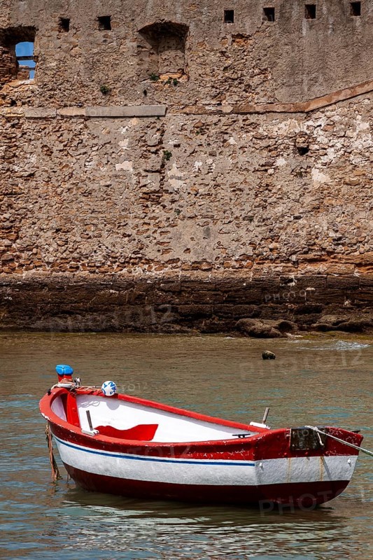Small fishing boat anchored in front of the historic city wall in Cadiz, Andalusia, Spain, Europe