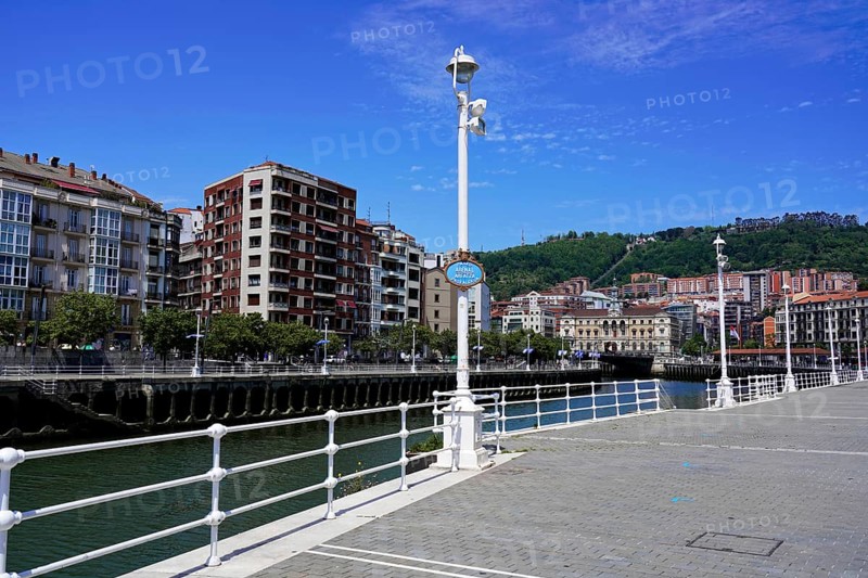 On the road in Bilbao, Bizkaia province, Basque Country, Spain, Europe, River bank with buildings and a bridge in a city, clear sky and calm, old town, Bilbao, Europe