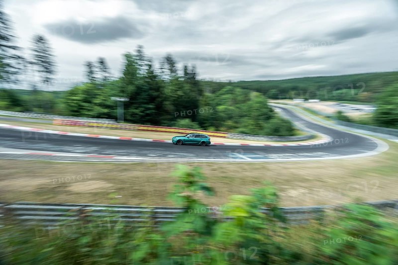 A car races around a racetrack with a bend with visible motion blur. Nuerburgring race track, Nuerburg Germany