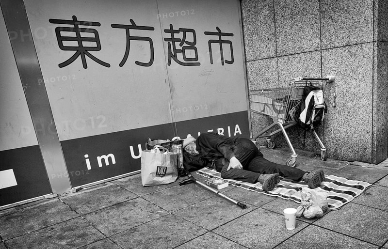 Homeless, Berber, sleeping, lying on pavement, Bible, shopping trolley, belongings, bag, Chinese characters, Asia Shop, Galeria Kaufhof, pedestrian zone, Koenigsstrasse, black and white, Stuttgart, Baden-Wuerttemberg, Germany, Europe