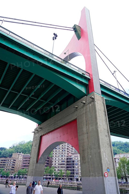 La Salve Bridge, A large bridge with red and green elements towering over buildings and pedestrians, Old Town, Bilbao, Basque Country, Spain, Europe