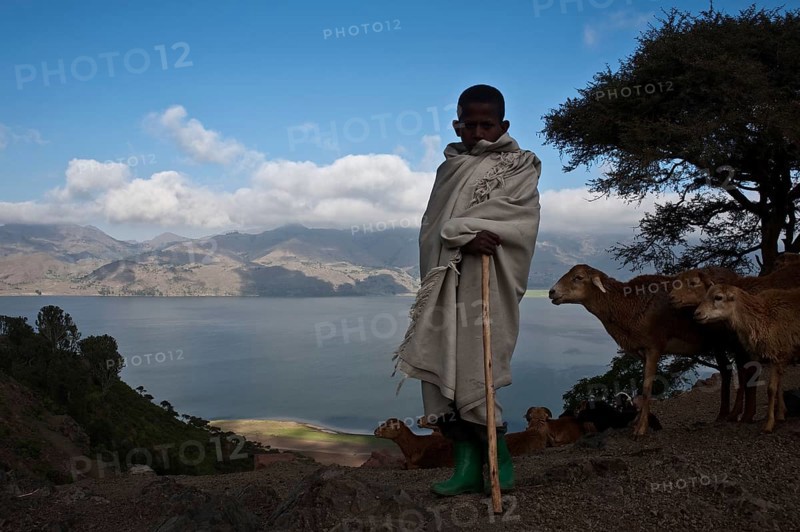 Boy working as a shepherd, Lake Hashenge in the background, Tigray state, Ethiopia. The boy is orthodox christian, his family is living in a very simple way that is reminiscent of the way the first chistians were living