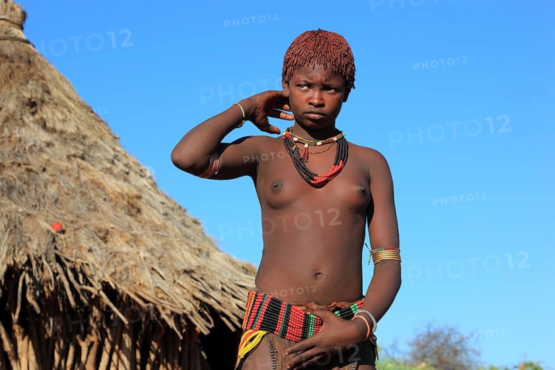 South Ethiopia, Omo region, young woman of the Hammer people standing in front of a round hut, dwelling, Ethiopia, Africa