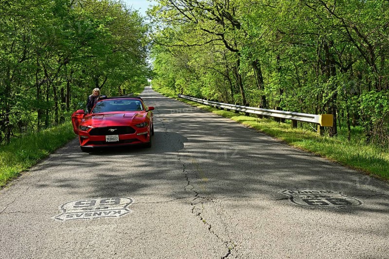 Red Ford Mustang parked on historic Route 66 in the middle of a forest in Kansas