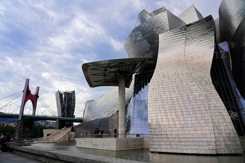 Guggenheim Museum, Bilbao, Basque Country, Spain, Europe, A modern building with shiny surfaces next to a bridge under a cloudy sky, Guggenheim Museum Bilbao on the banks of the river Nervion, architect Frank O. Gehry, Europe