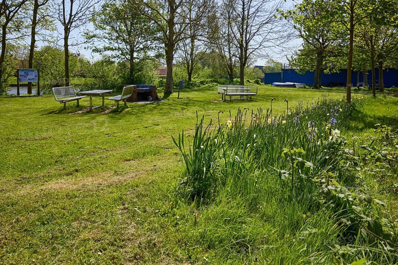 Small park with flowers, lawn and a public barbecue area with brick barbecue, benches and tables in Friedrichstadt, Nordfriesland district, Schleswig-Holstein, Germany, Europe
