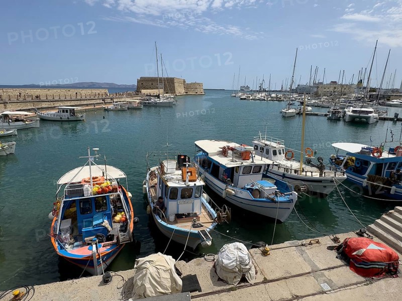 Several small fishing boats in historic Venetian harbour of Heraklion, left in the background historic fortress built in the Middle Ages 16th century by Republic of Venice old name Castello Rocca al Mare today Koules in harbour of Iraklion, Heraklion, Crete, Greece, Europe