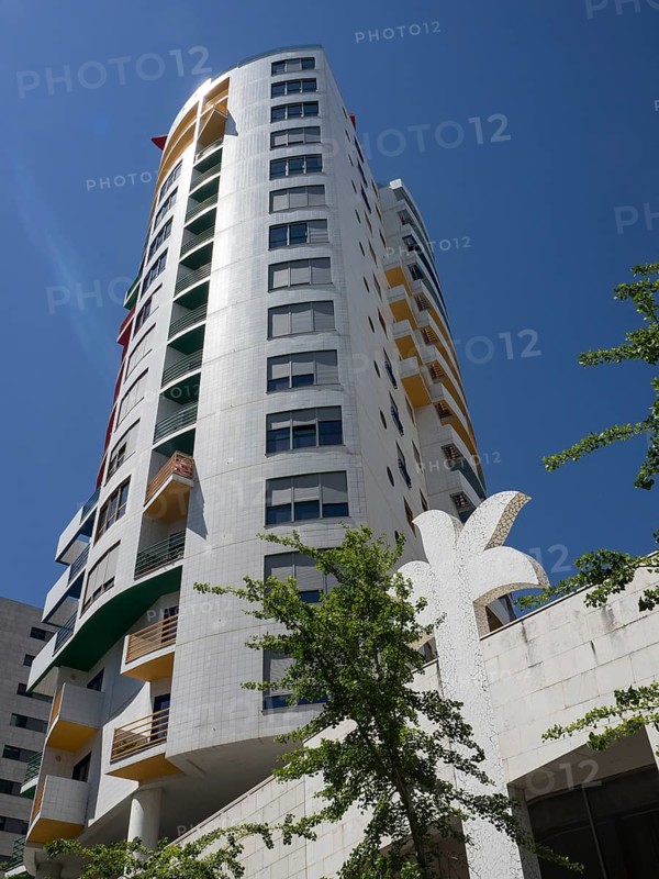 A modern high-rise building with balconies and colourful elements under a clear blue sky, Lisbon, Portugal, Europe