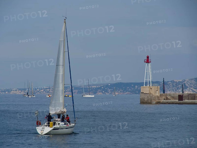 Sailing boat on the open sea, in the background more boats and a lighthouse, Marseille on the Mediterranean Sea with the old cathedral and ships in the historic harbour, rocky coast on the Mediterranean Sea, marseille, france