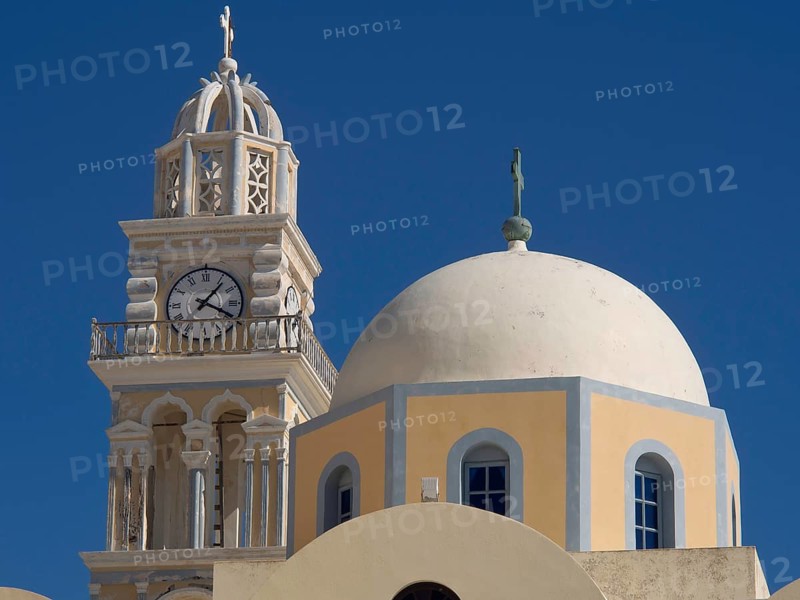 A church tower with a clock and a domed church with a cross against a clear blue sky, The volcanic island of Santorini with blue and white houses and churches, flowers and the deep blue sea, Santorini, Greece, Europe