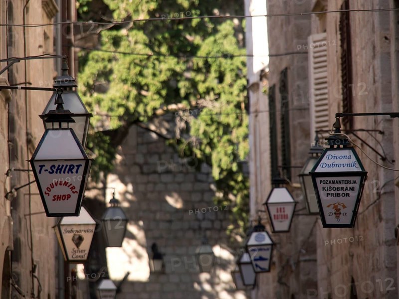 Old town street with hanging lanterns and shop signs, the old town of Dubrovnik with historic houses, churches, red roofs and fortress walls, dubrovnik, coratia