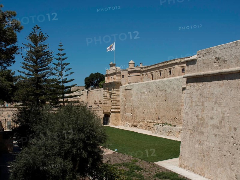 Historic fortress with protective stone walls, wide green spaces and a waving flag under a bright blue sky, the town of mdina on the island of malta with historic houses, colourful balconies, magnificent churches, mdina, Malta, Europe
