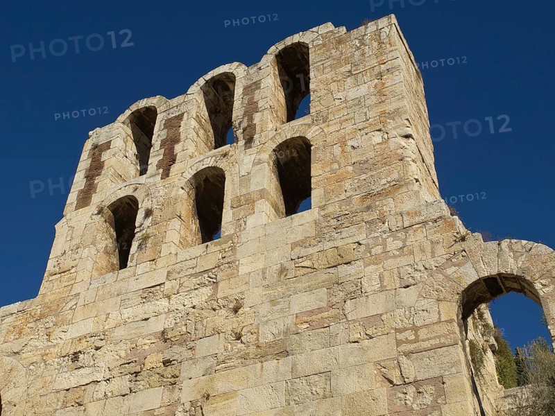 Ancient stone structure with several arches in front of blue sky, Ancient building with columns and trees on the Acropolis in Athens in front of blue sky, athens, greece