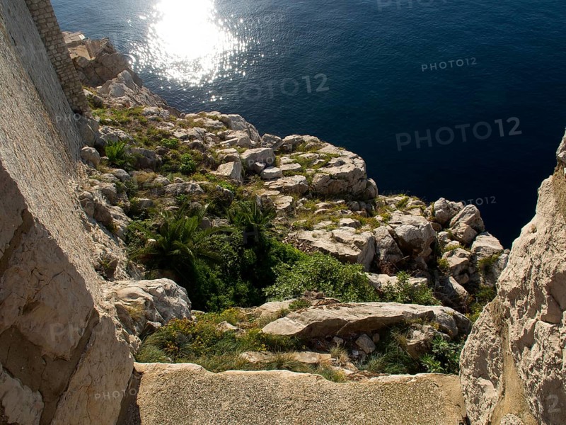 Rocky coast sloping into the sunny sea, the old town of Dubrovnik with historic houses, churches, red roofs and fortress walls, dubrovnik, coratia