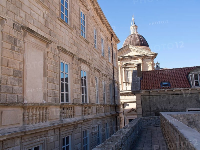 Old buildings with stone walls and many windows, in the background a dome under a blue sky, the old town of Dubrovnik with historic houses, churches, red roofs and fortress walls, dubrovnik, coratia
