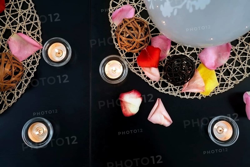 Table decoration with candles, wicker balls and rose petals
