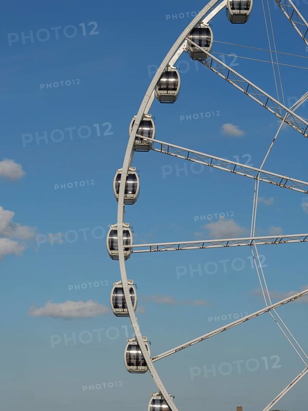 Partial view of a Ferris wheel with several cabins in front of a clear blue sky, the beach of scheveningen with pier and the promenade, scheveningen, the netherlands