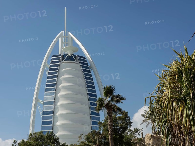 The Burj Al Arab Hotel in Dubai with palm trees and green spaces in the foreground, dubai, arab emirates