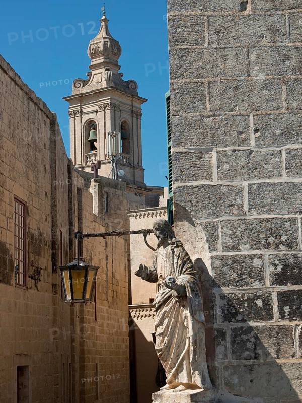 Street with historic architecture, sculpture and church tower in the background, the town of mdina on the island of malta with historic houses, colourful balconies, magnificent churches, mdina, Malta, Europe