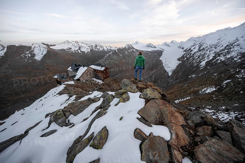 Hiker looking at mountain panorama and glacier, mountain hut Ramolhaus with snow, view of Gurgler Ferner with summit Hochwilde and Falschungsspitze, Oetztal Alps, Tyrol, Austria, Europe
