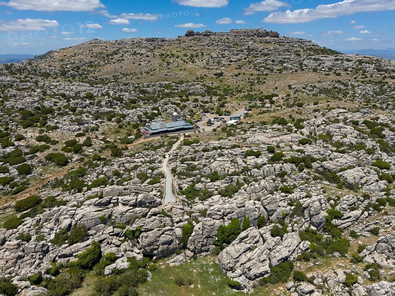 A rocky and dry landscape with two buildings under a cloudy sky, aerial view, karst mountains, Torcal Alto, El Torcal de Antequera, Sierra del Torcal, Malaga, Andalusia, Spain, Europe