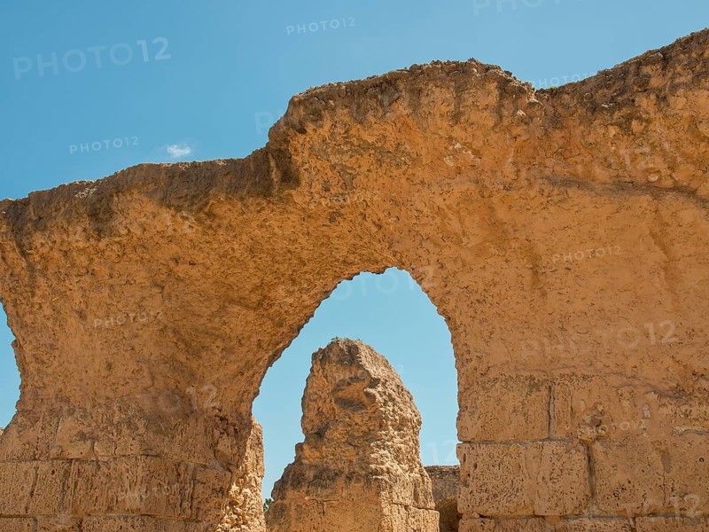 Ancient stone ruins with a large arch, blue sky in the background, Tunis in Africa with ruins from Roman times, modern mosques and blue and white houses in sidi-bou-said, Tunis, Tunisia, Africa
