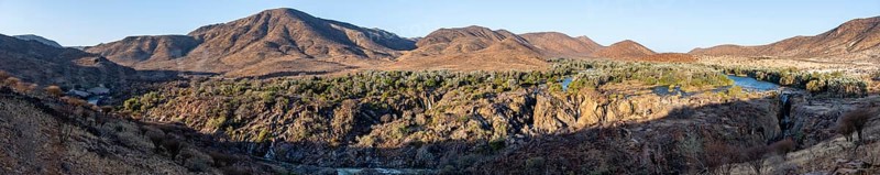 Panorama, Kunene River with green vegetation in dry red mountain landscape, waterfall and African Baobab (Adansonia digitata), in the evening light, Epupa Falls, Kunene, Namibia, Africa