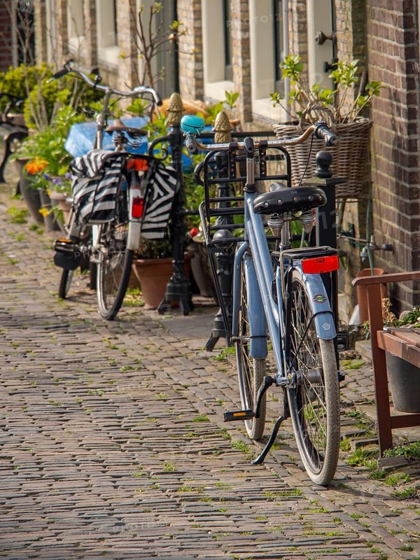 Bicycles parked in a quiet, cobbled street in the old town, historic houses in Hoorn and ships in the harbour, hoorn, the netherlands