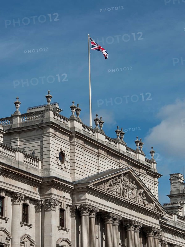 Historic building with a waving Union Jack flag on the roof, against a blue sky, London, England, United Kingdom, Europe