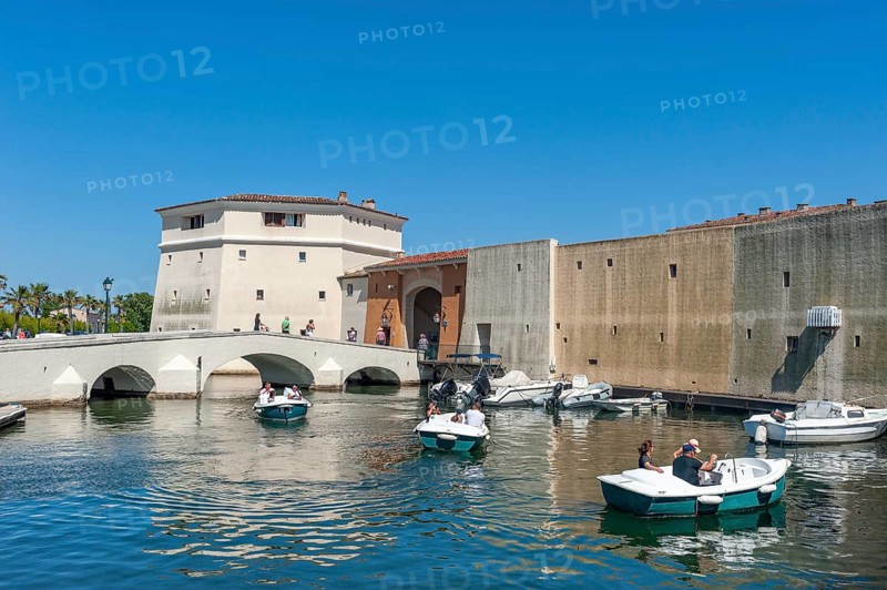 Bachelor tower, Tour des Celibataires, at the Pont de la Poteme bridge. In the foreground, tourists in electric boats, Port Grimaud, Var, Provence-Alpes-Cote d Azur, France, Europe