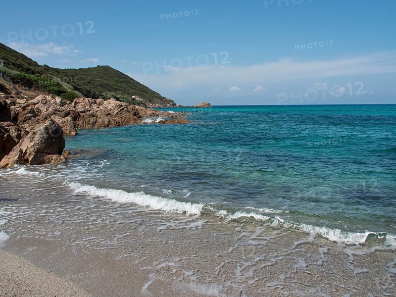 Beach with rocks, gentle waves and clear blue water under a sunny sky, Corsica, Ajaccio, France, Europe