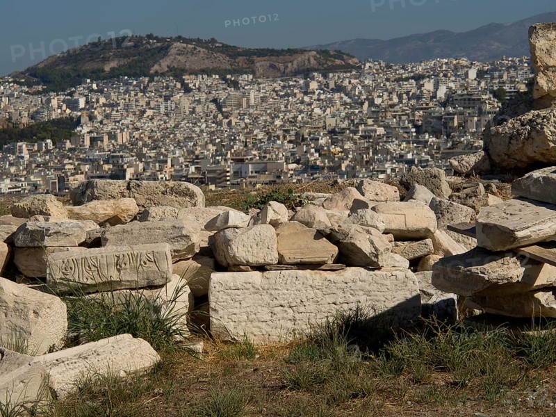Ancient stones and ruins with a view of the city and surrounding mountains, Ancient buildings with columns and trees on the Acropolis in Athens against a blue sky, athens, greece
