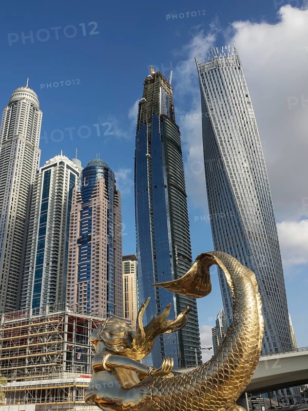 View of modern skyscrapers with a golden mermaid statue in the foreground and a clear blue sky, Dubai, Arab Emirates