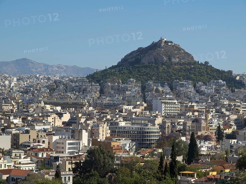 City view with buildings and a hill in the background in clear weather, Ancient buildings with columns and trees on the Acropolis in Athens against a blue sky, athens, greece