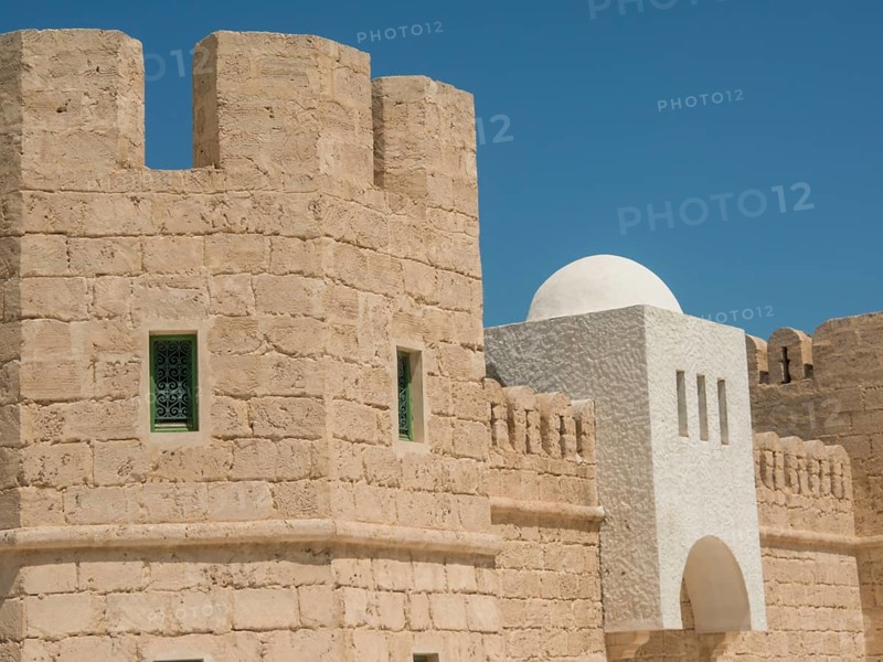 Sand-coloured fortress with green-framed windows and white dome under a blue sky, Tunis in Africa with ruins from Roman times, modern mosques and blue and white houses in sidi-bou-said, Tunis, Tunisia, Africa