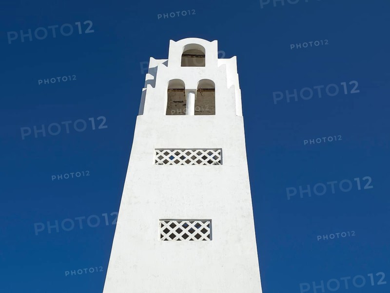 A white bell tower in minimalist style against a bright blue sky, The volcanic island of Santorini with blue and white houses and churches, flowers and palm trees on a volcanic island, santorini, greece