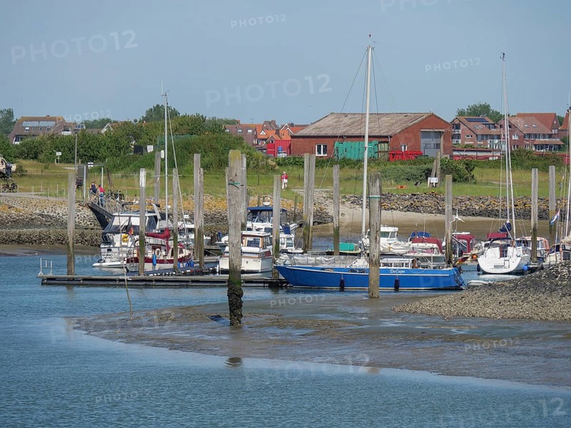 Harbour with sailing boats and houses on the shore under a clear blue summer sky, Baltrum Germany