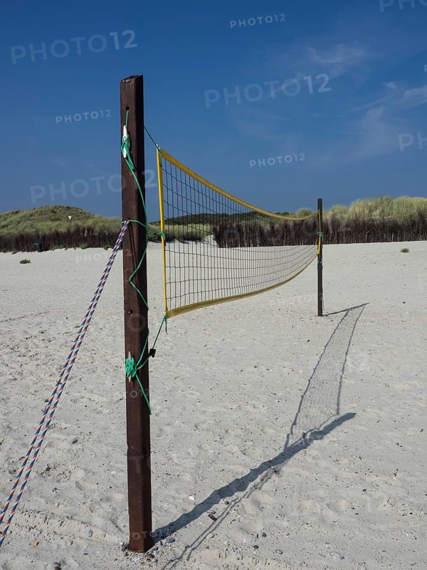 A volleyball net is set up in the sand on the beach, surrounded by dunes and grass, Heligoland, Germany, Europe