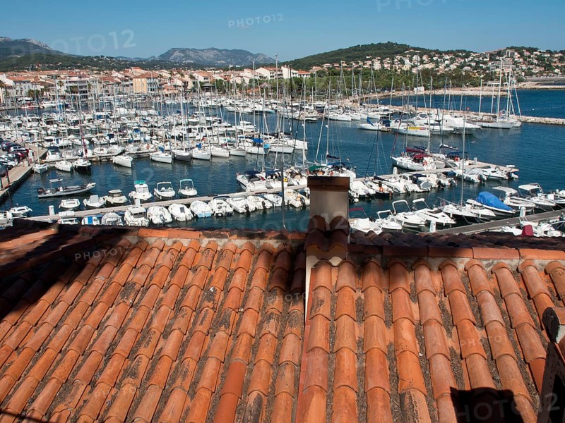 View from a rooftop onto a busy marina with many boats and houses on the hillside, la seyne sur mer, france